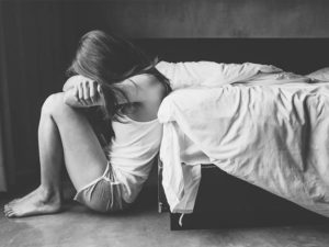Portrait of depressed woman sitting alone on the floor in the bedroom.