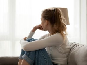 Upset woman sitting on couch alone at home